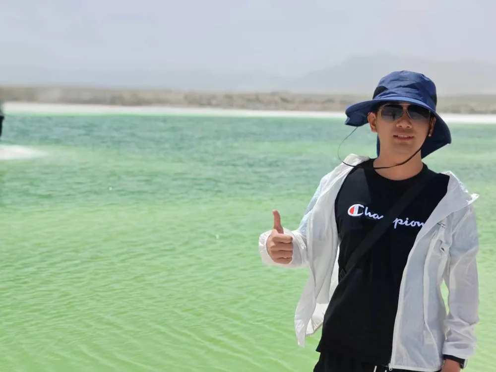 Ethan wearing a sun hat beside turquoise water.