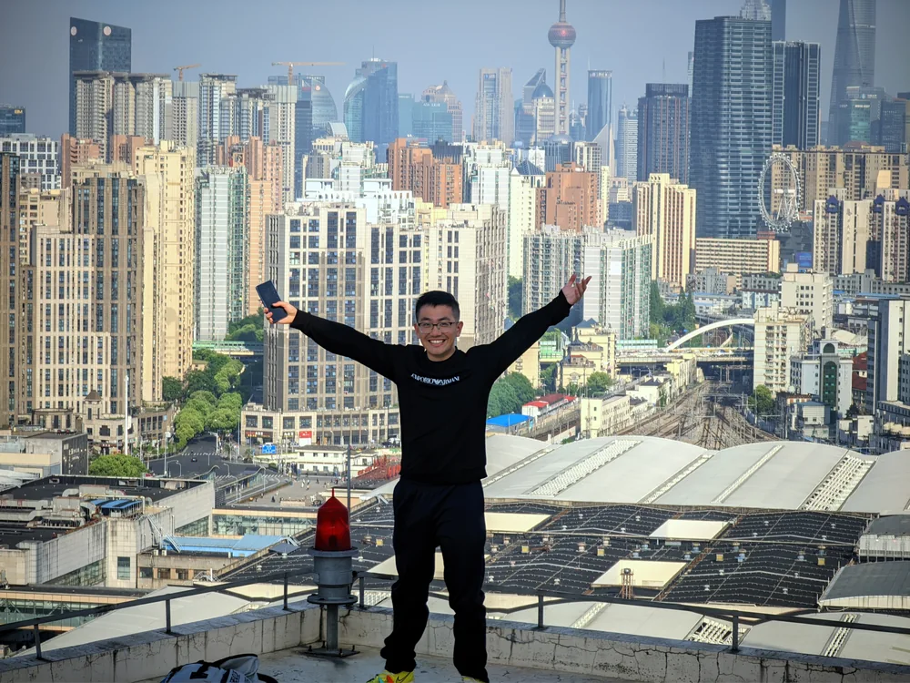 Ethan standing with his arms raised in front of a city skyline.