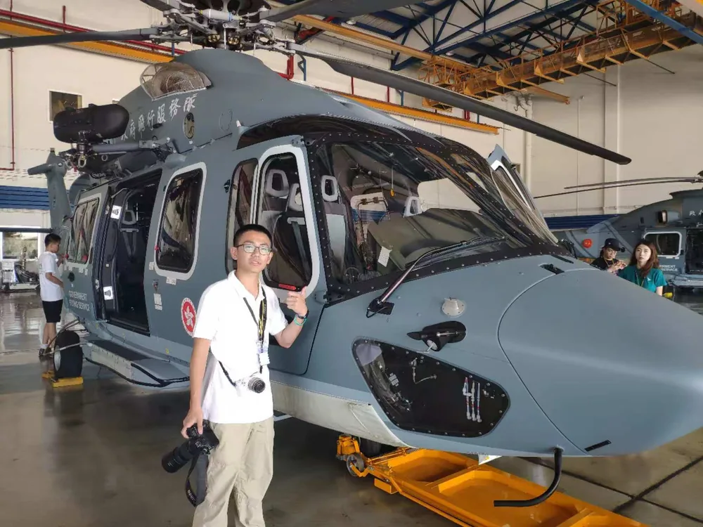 Ethan beside a helicopter inside a hangar.